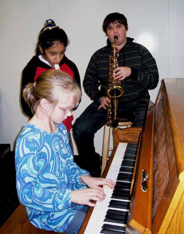Elementary students developing musical skills through piano and instrumental instruction