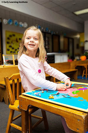 Preschool child building cognitive skills through puzzle-based learning at a classroom table