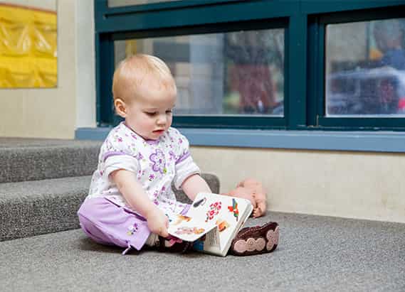 Toddler exploring a book during independent learning time in a preschool environment
